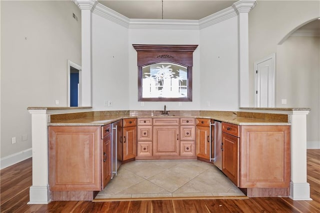 kitchen with sink, light hardwood / wood-style flooring, ornamental molding, light stone counters, and kitchen peninsula