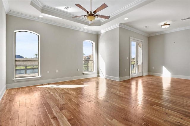 unfurnished room featuring a tray ceiling, crown molding, ceiling fan, and hardwood / wood-style flooring