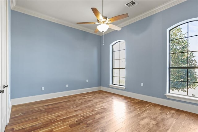 spare room featuring hardwood / wood-style floors, ornamental molding, and a healthy amount of sunlight