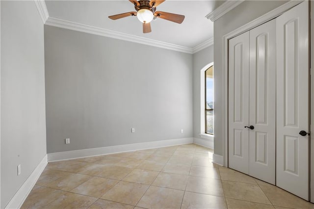 unfurnished bedroom featuring ceiling fan, a closet, light tile patterned floors, and ornamental molding