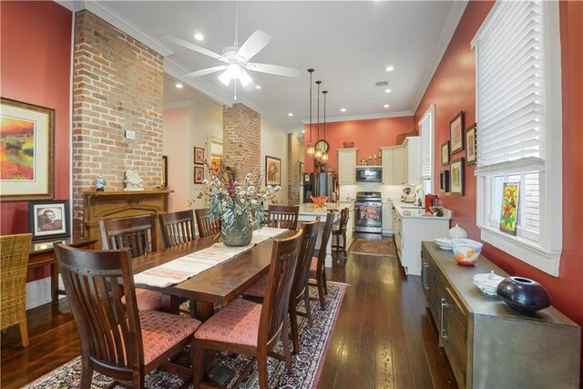 dining area with ceiling fan, dark hardwood / wood-style flooring, crown molding, and a brick fireplace