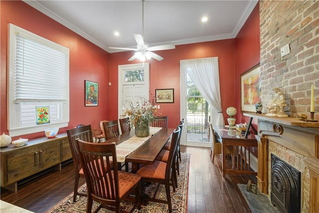 dining room featuring a fireplace, crown molding, ceiling fan, and dark wood-type flooring