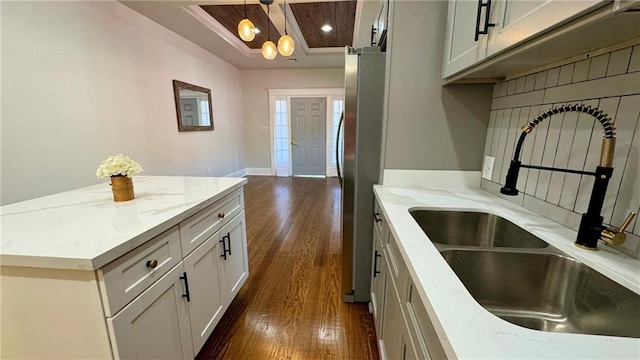 kitchen featuring light stone countertops, dark hardwood / wood-style flooring, stainless steel refrigerator, and sink