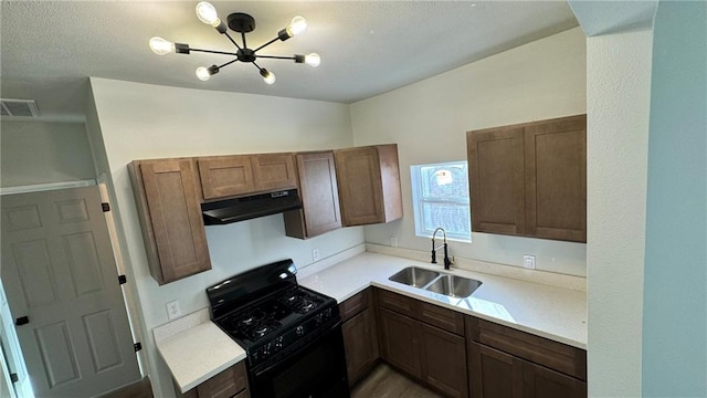 kitchen featuring black gas range oven, extractor fan, a notable chandelier, and sink