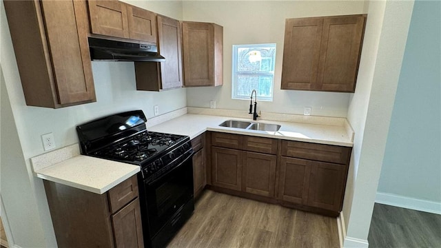 kitchen featuring black range with gas stovetop, wood-type flooring, and sink