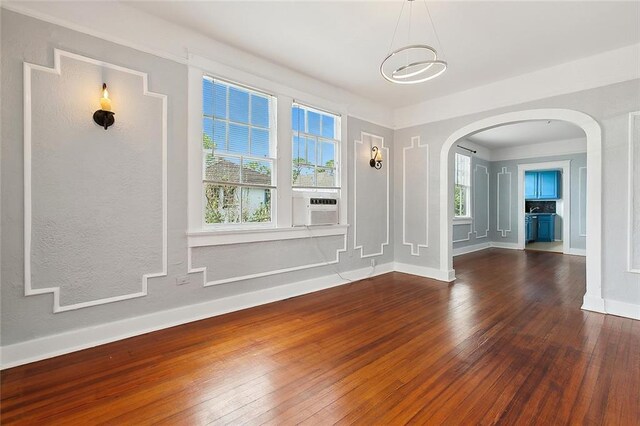 unfurnished room with a notable chandelier, cooling unit, and dark wood-type flooring