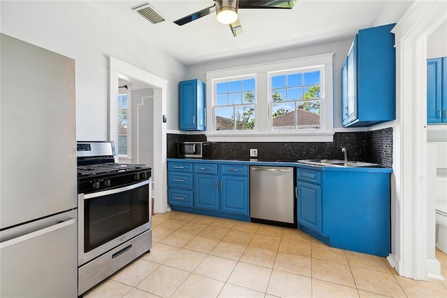 kitchen with blue cabinets, sink, ceiling fan, light tile patterned floors, and stainless steel appliances