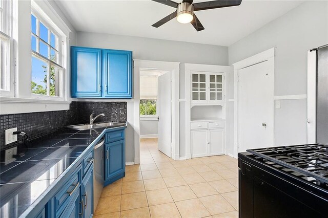 kitchen with sink, stainless steel dishwasher, decorative backsplash, light tile patterned floors, and blue cabinetry