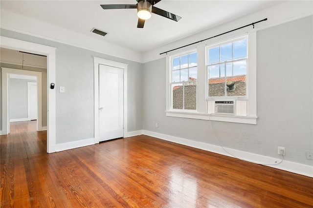 unfurnished bedroom featuring hardwood / wood-style floors, ceiling fan, and cooling unit