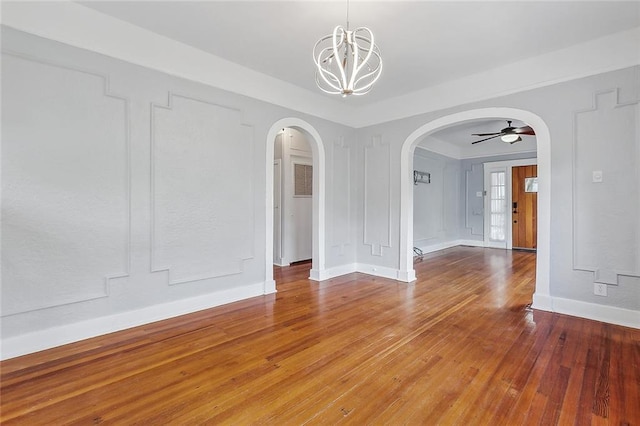 empty room featuring ceiling fan with notable chandelier and wood-type flooring