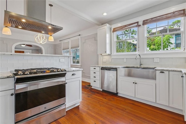 kitchen with ventilation hood, decorative backsplash, white cabinetry, and stainless steel appliances