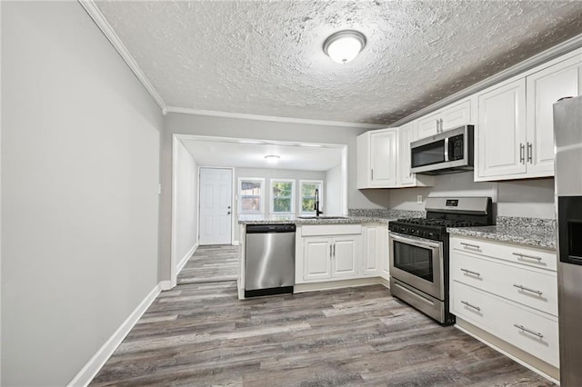 kitchen featuring white cabinets, appliances with stainless steel finishes, and hardwood / wood-style flooring