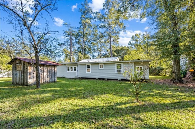 rear view of property featuring a yard and a storage shed