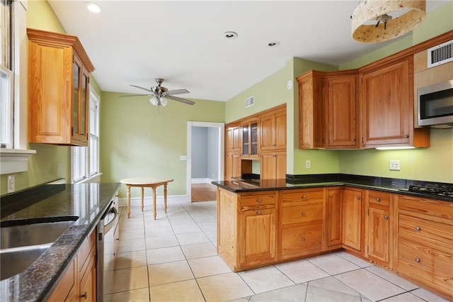 kitchen with ceiling fan, light tile patterned floors, dark stone counters, and appliances with stainless steel finishes