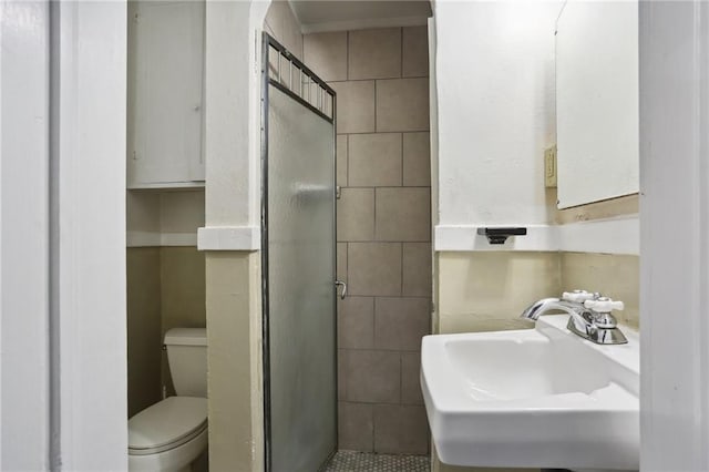 bathroom featuring tile patterned floors, toilet, a shower with door, and sink