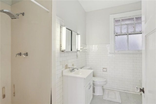 bathroom with tile patterned floors, vanity, a shower, tile walls, and toilet