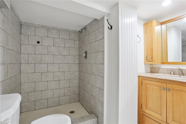 bathroom featuring toilet, a tile shower, and vanity