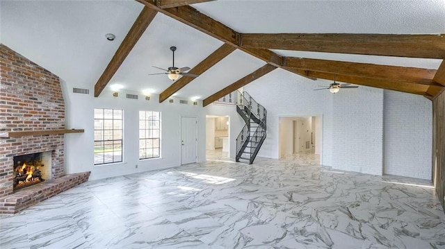 unfurnished living room featuring ceiling fan, beam ceiling, brick wall, and a brick fireplace