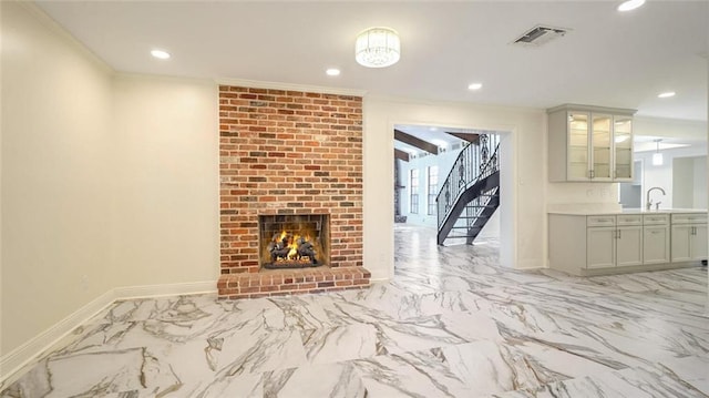 living room with sink, ornamental molding, and a fireplace