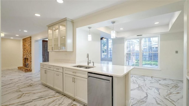 kitchen featuring dishwasher, sink, a brick fireplace, decorative light fixtures, and kitchen peninsula