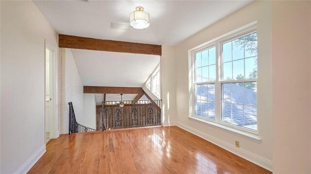 bonus room with wood-type flooring, lofted ceiling with beams, and plenty of natural light