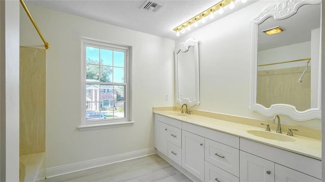 bathroom with hardwood / wood-style floors, vanity, washtub / shower combination, and a textured ceiling