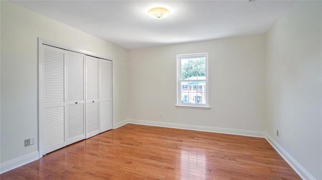 unfurnished bedroom with light wood-type flooring and a closet