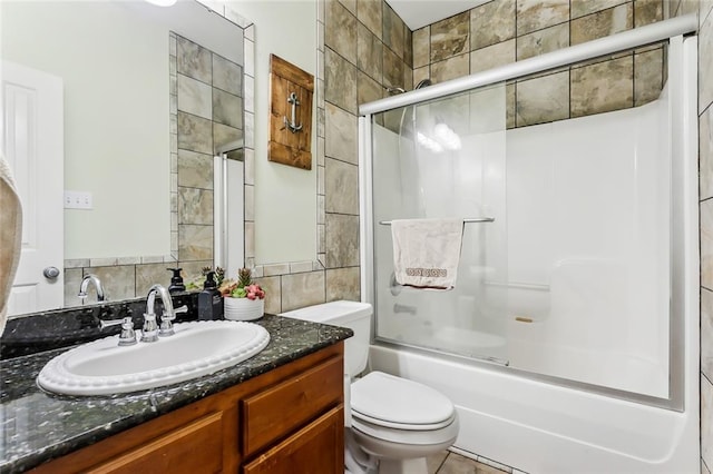 full bathroom featuring vanity, toilet, tile walls, and bath / shower combo with glass door