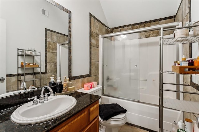 full bathroom featuring lofted ceiling, toilet, shower / bath combination with glass door, vanity, and tile walls