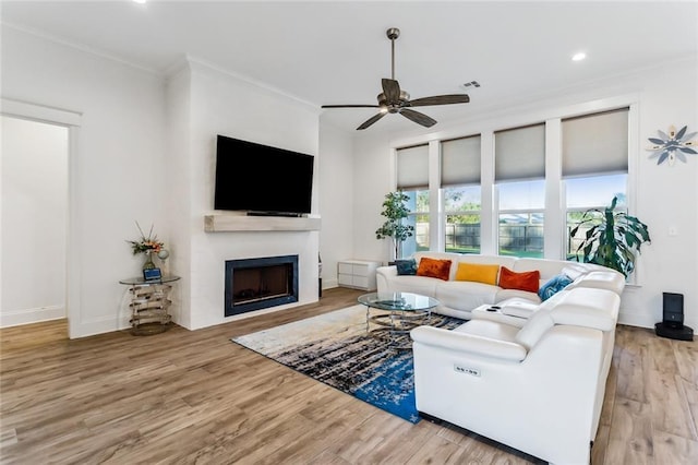 living room with a fireplace, crown molding, ceiling fan, wood finished floors, and baseboards