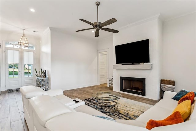 living area featuring ceiling fan, recessed lighting, a fireplace, wood finished floors, and ornamental molding