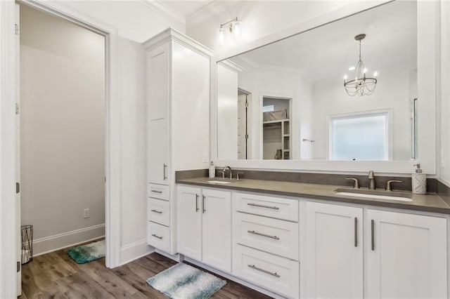 full bathroom featuring double vanity, ornamental molding, wood finished floors, a sink, and a notable chandelier