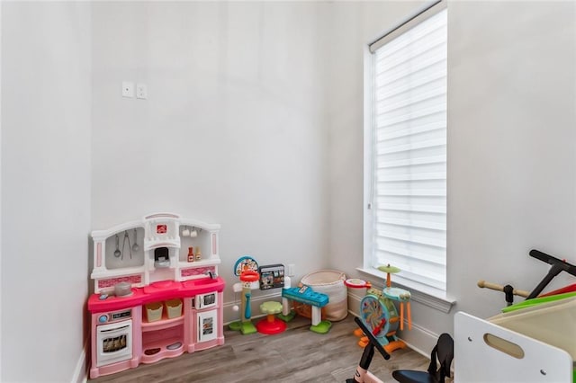 recreation room featuring a healthy amount of sunlight, baseboards, and wood finished floors