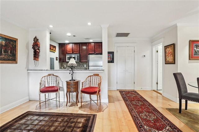 610 N Rampart St Unit F, New Orleans, LA 70112 - kitchen featuring appliances with stainless steel finishes, reddish brown cabinets, light wood-style flooring, decorative backsplash, and ornamental molding