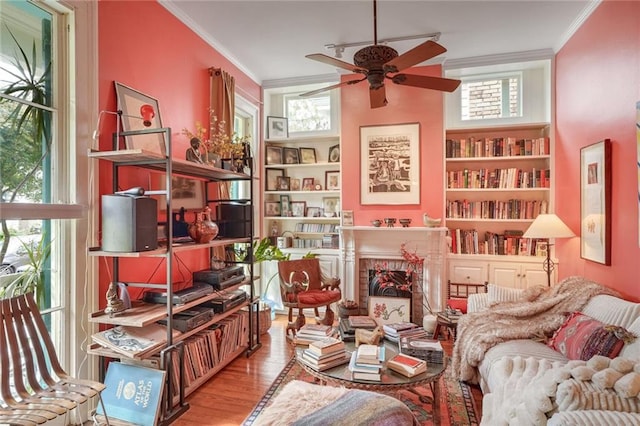 sitting room with ceiling fan, a fireplace, light wood-type flooring, and crown molding