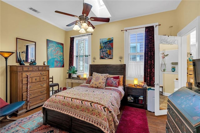 bedroom with a skylight, ceiling fan, and hardwood / wood-style floors