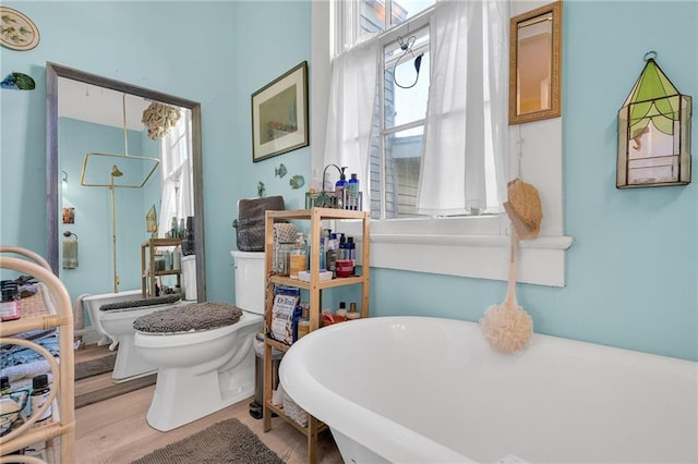 bathroom featuring toilet, wood-type flooring, and a bath