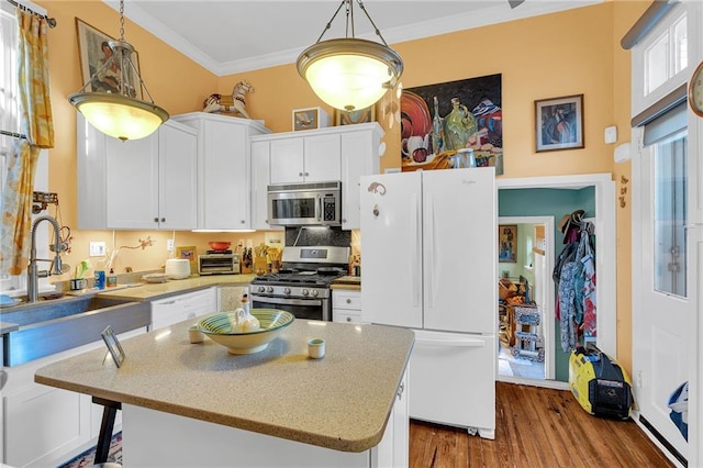 kitchen featuring appliances with stainless steel finishes, crown molding, white cabinets, hardwood / wood-style floors, and a kitchen island