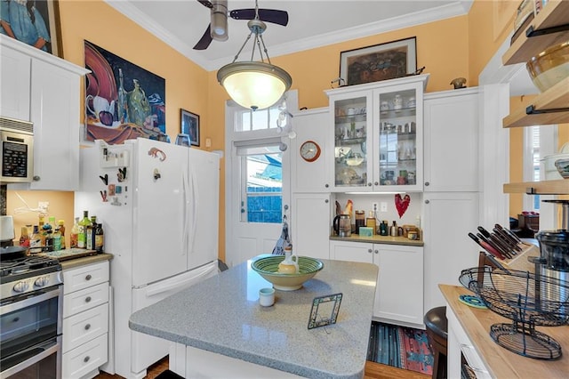 kitchen featuring stainless steel appliances, light stone counters, pendant lighting, white cabinets, and ornamental molding