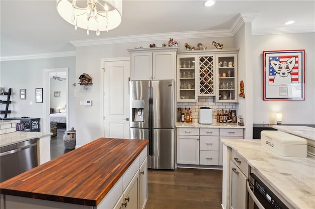 kitchen featuring appliances with stainless steel finishes, backsplash, butcher block countertops, and dark hardwood / wood-style flooring