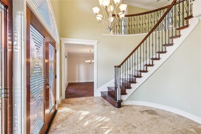 entrance foyer with crown molding, a high ceiling, and an inviting chandelier