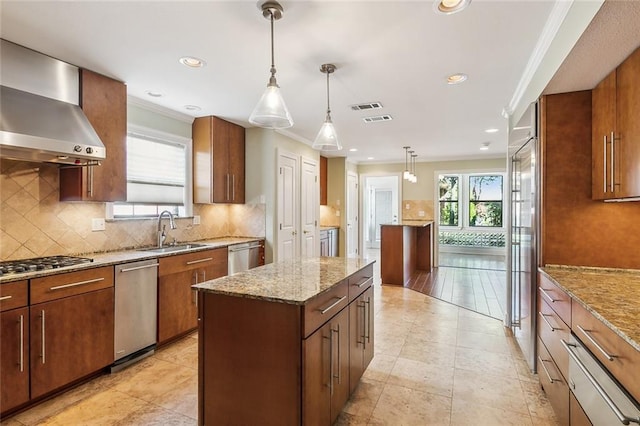 kitchen with crown molding, sink, wall chimney exhaust hood, decorative light fixtures, and a kitchen island