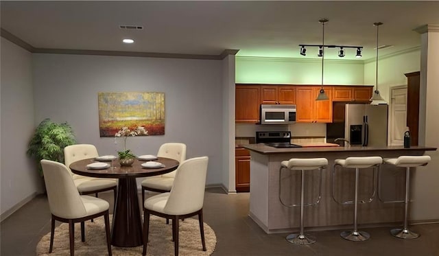 kitchen with a breakfast bar, a center island, ornamental molding, appliances with stainless steel finishes, and pendant lighting