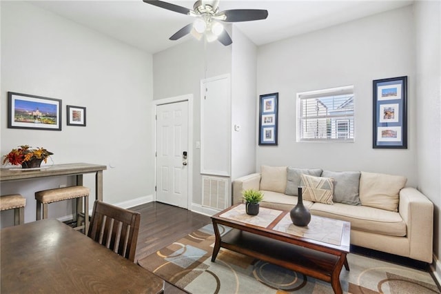 living room featuring ceiling fan and dark wood-type flooring