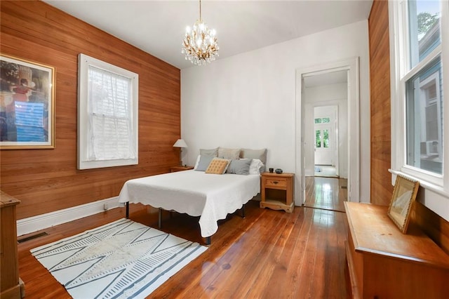 bedroom featuring multiple windows, wood walls, and dark hardwood / wood-style flooring