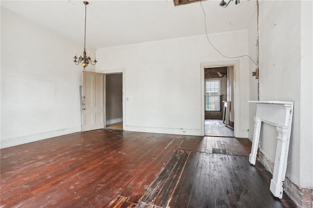 unfurnished living room featuring dark hardwood / wood-style flooring, a fireplace, and an inviting chandelier