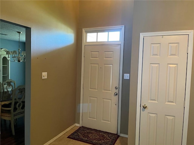 tiled entrance foyer featuring a textured ceiling and an inviting chandelier