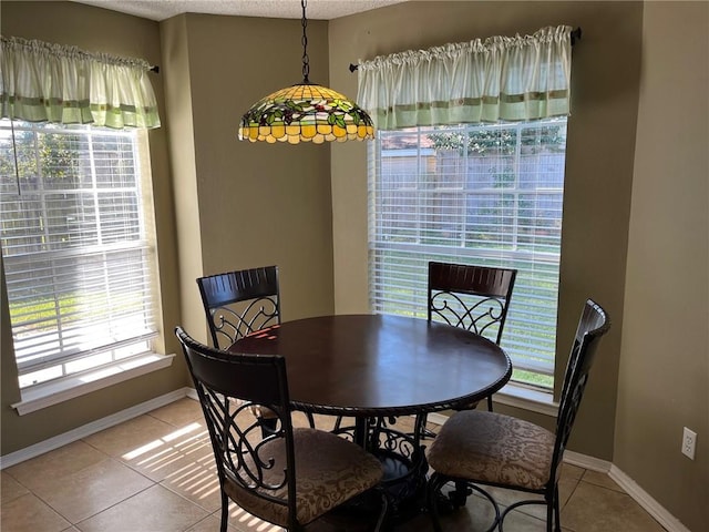 tiled dining space with a textured ceiling and a wealth of natural light