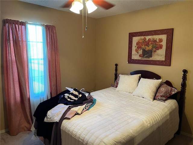 carpeted bedroom featuring ceiling fan and a textured ceiling