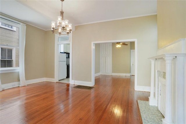 unfurnished dining area featuring ceiling fan with notable chandelier, wood-type flooring, and ornamental molding